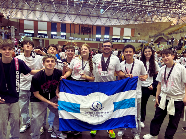 No foto vemos a equipe do Colégio Salvatoriano Fátima comemorando com a bandeira do Colégio os resultados durante Olimpíadas de História do Brasil.